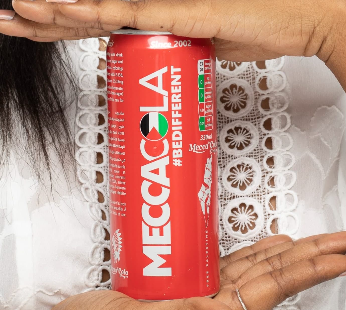 Canette Mecca Cola tenue entre deux mains