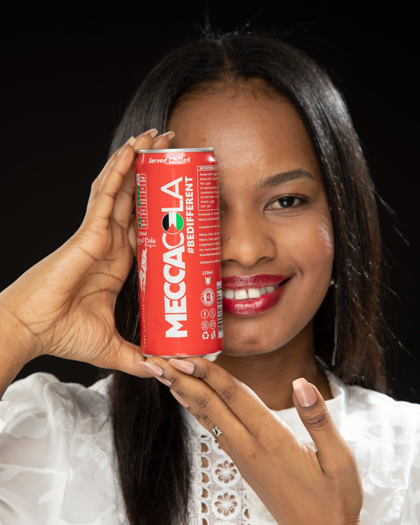 Une femme tient une canette Mecca-Cola devant son visage